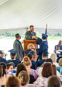 Graduate receiving diploma and shaking hands with man at the podium.