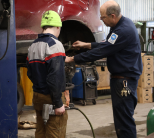 Student and teacher working on fixing a tire in automotive class