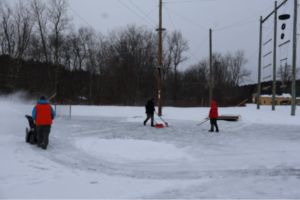 students in boots playing hockey on an ice rink
